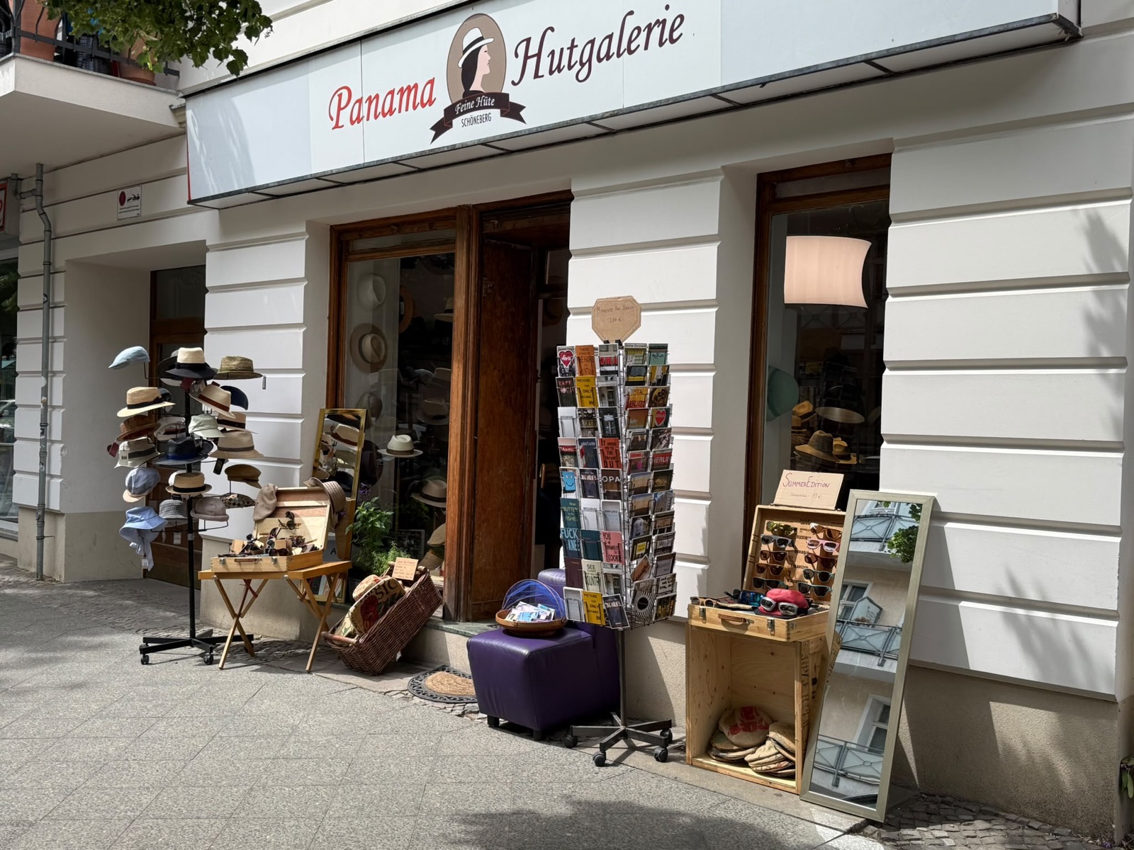 Eingang der Panama Hutgalerie mit Hutständern und Postkarten vor der Tür
